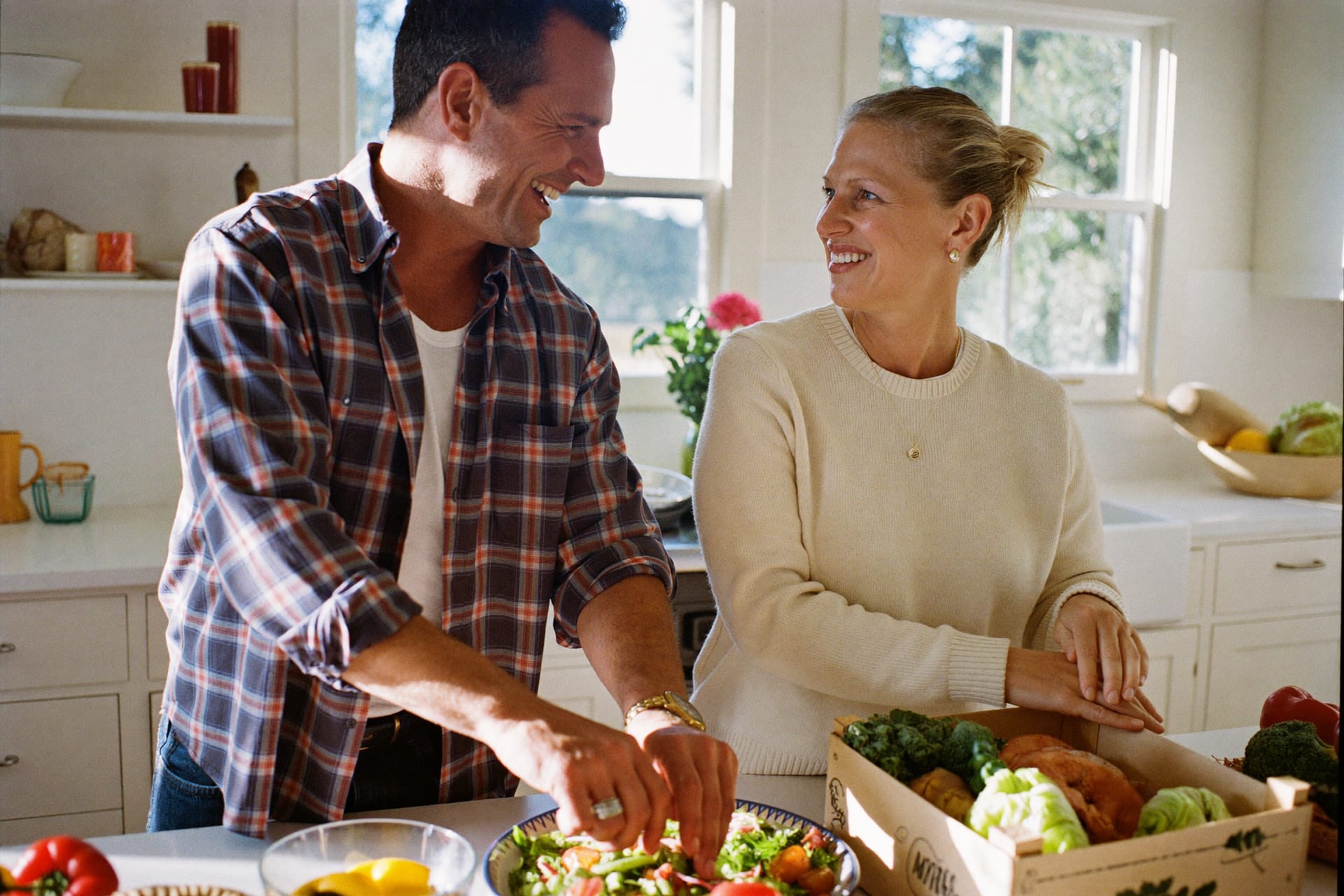 A couple preparing a colorful whole-food meal in a bright kitchen