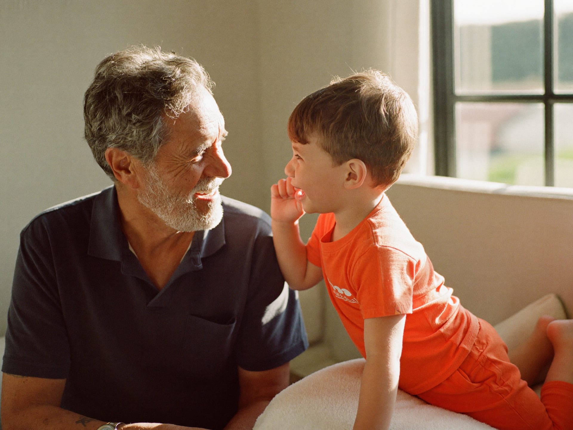 A grandfather delighting in his grandchild's whisper