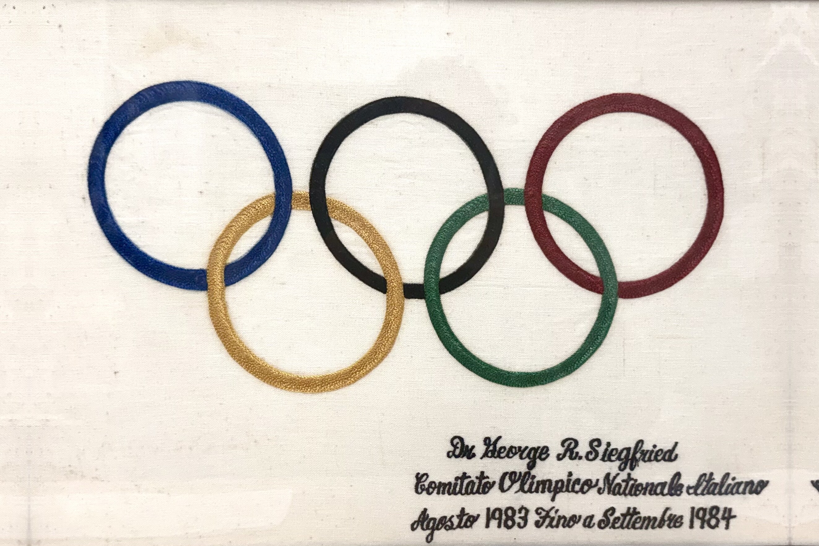 An embroidered Olympic rings banner presented to Dr. George R. Siegfried by the Comitato Olimpico Nazionale Italiano, August 1983 to September 1984