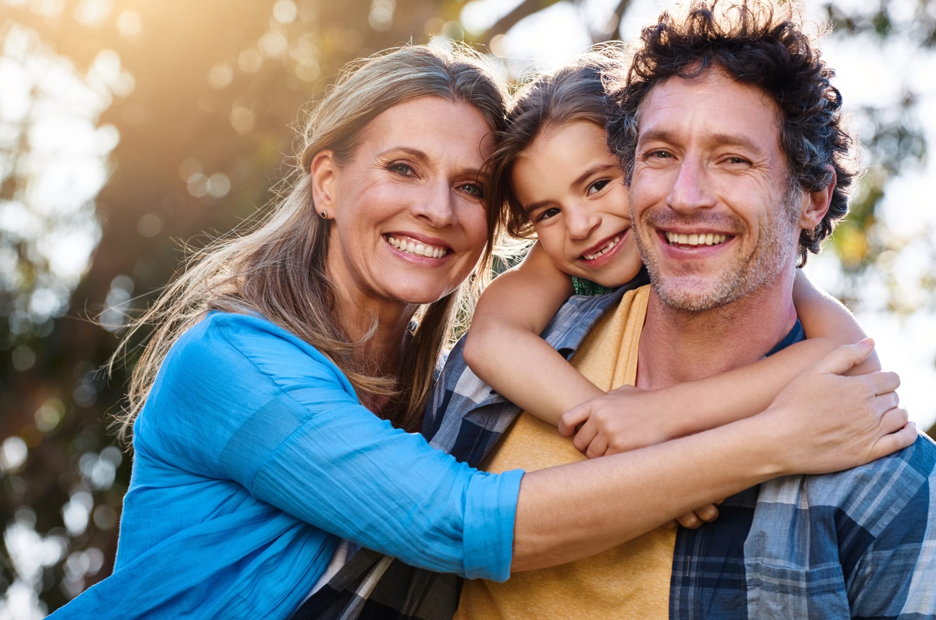 A happy family smiling together outdoors in bright sunlight